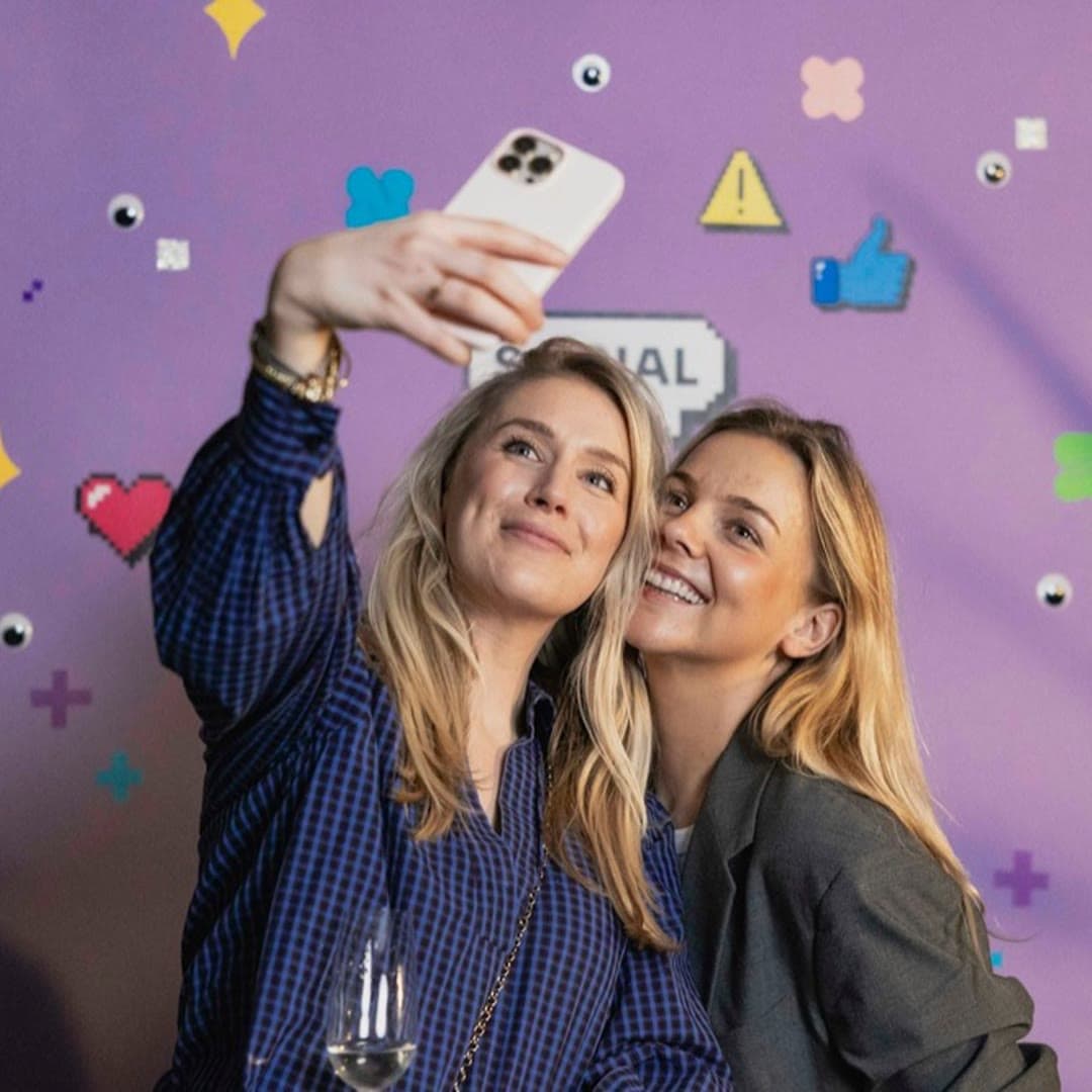Twee collega’s maken een selfie voor de paarse wand